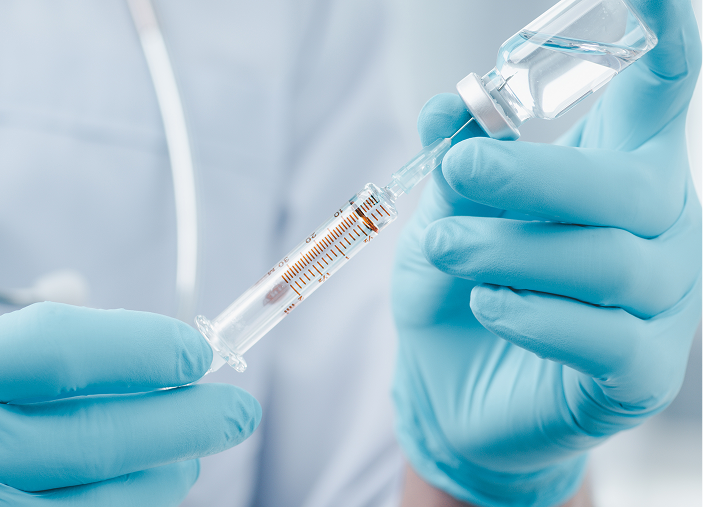 Photo of gloved hands holding a syringe